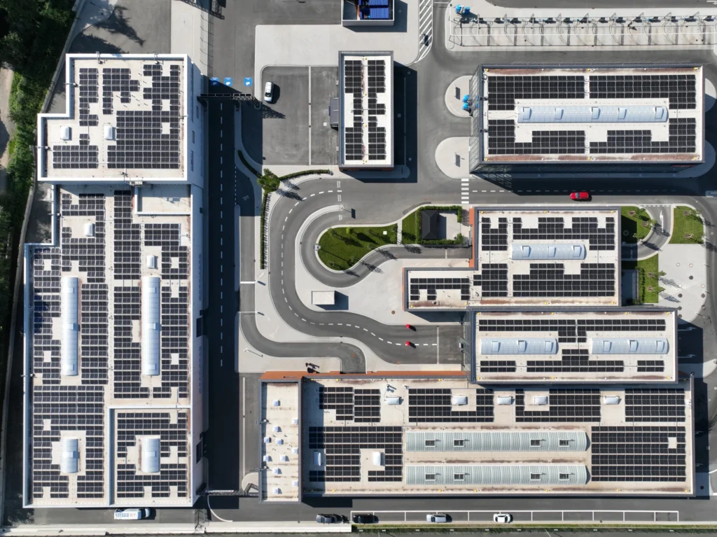 Solarmodule bedecken Gebäude, die von Straßen umgeben sind; Vogelperspektive auf einem sonnigen Tag.