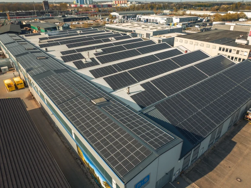Solarmodule bedecken die Dächer großer Lagerhallen in einem Industriegebiet bei sonnigem Wetter.