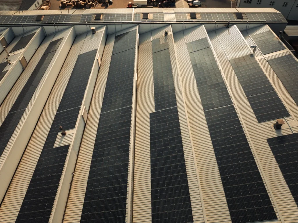 Solarmodule reflektieren Sonnenlicht auf Fabrikdach, industrielles Umfeld, klare, parallele Paneelanordnung.