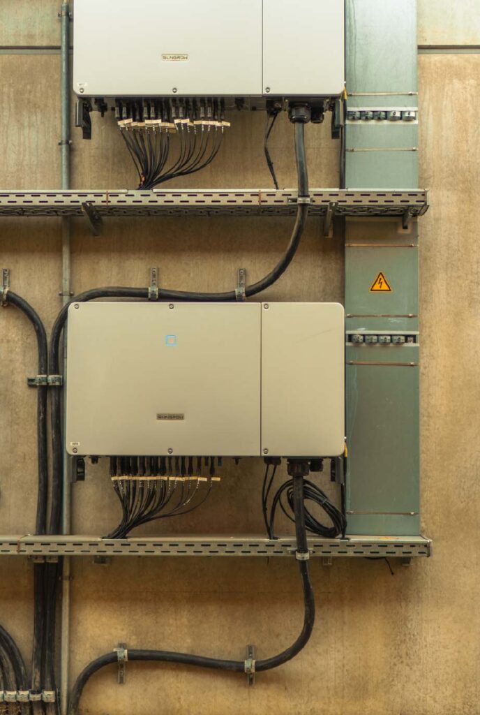 Zwei graue elektronische Geräte hängen an der Wand, Kabel verlaufen darunter und seitlich.