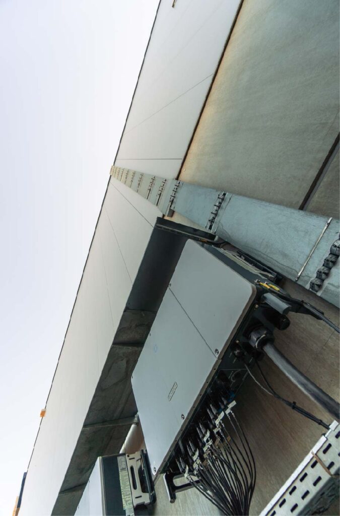 Metallkästen hängen mit Kabeln an einer Hauswand, perspektivisch nach oben fotografiert.