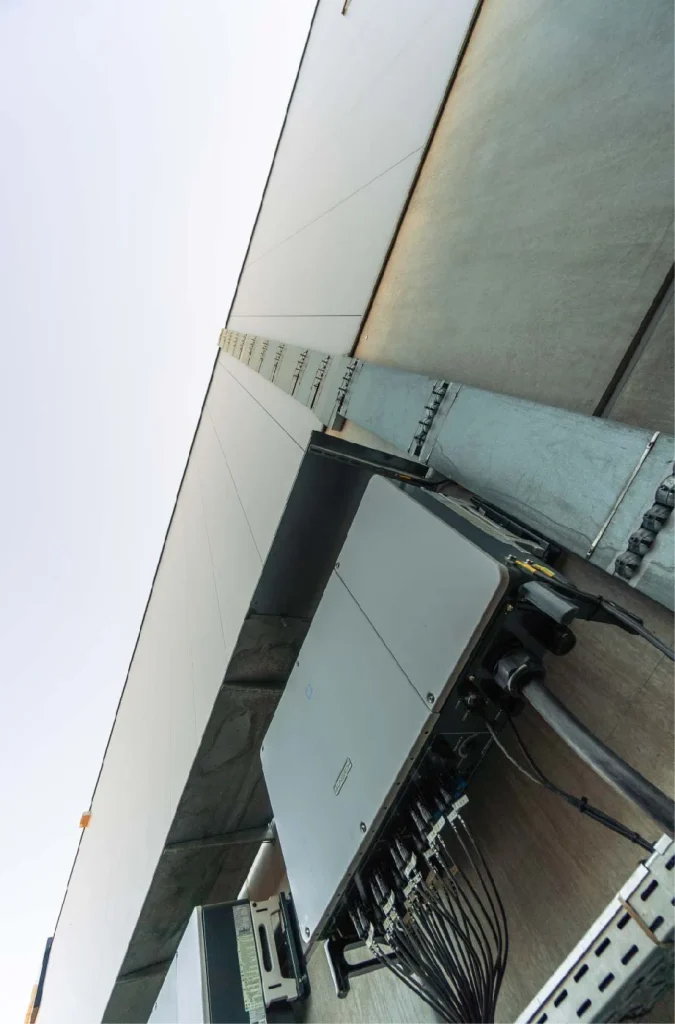 Metallkästen hängen mit Kabeln an einer Hauswand, perspektivisch nach oben fotografiert.