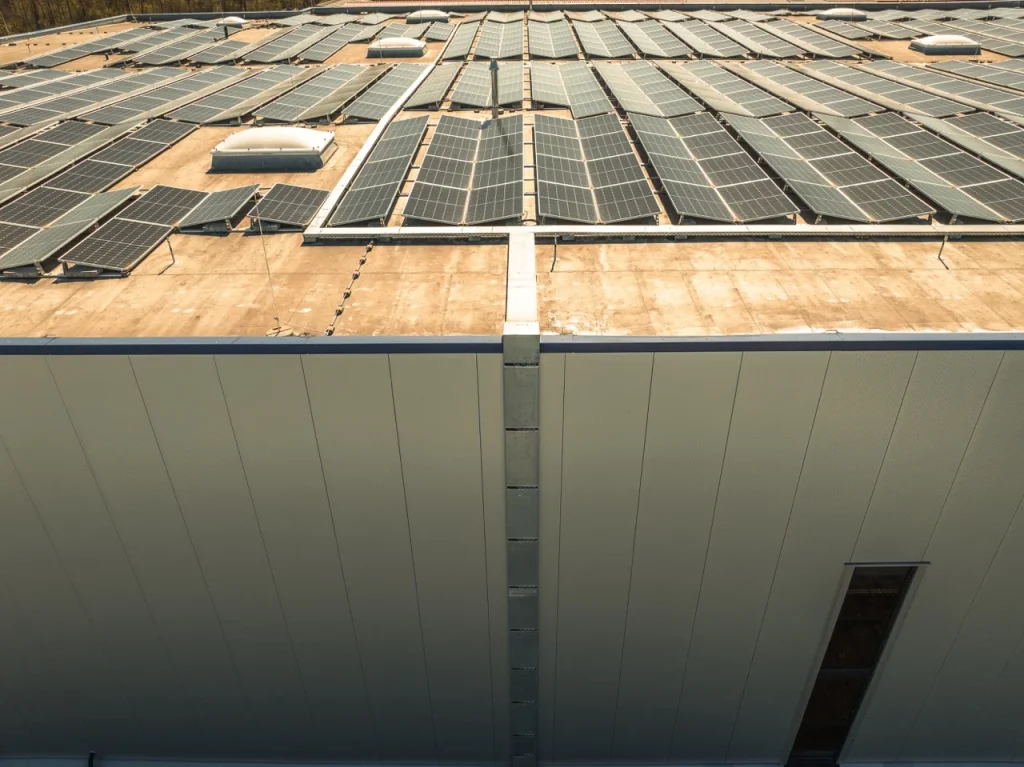 Solarmodule bedecken das Dach eines großen Gebäudes bei Tageslicht.