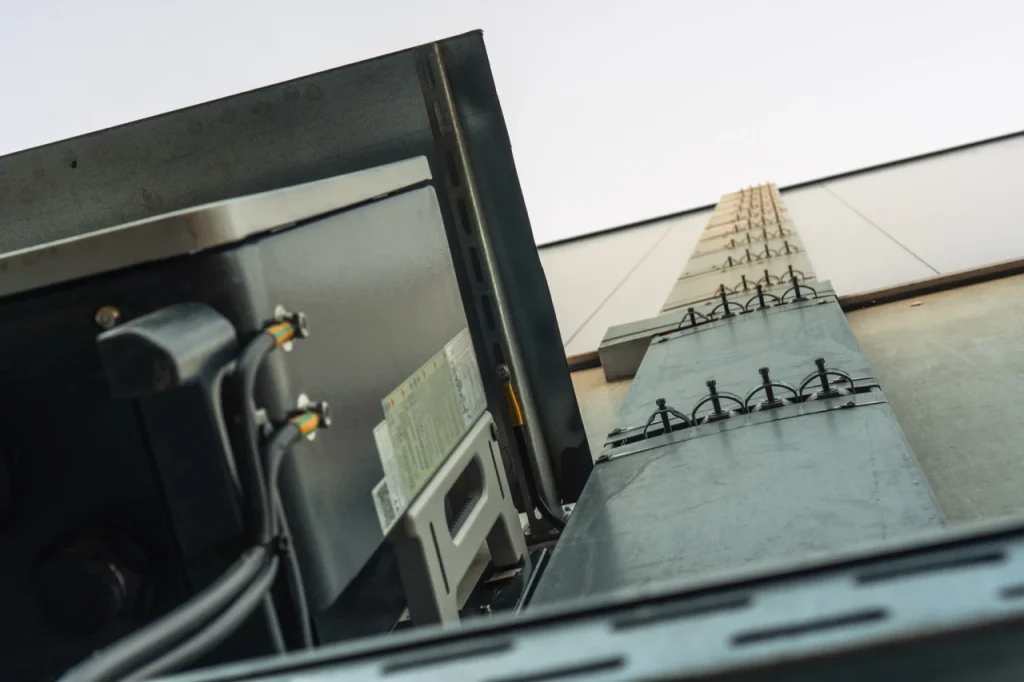 Metallkabelkanal erhebt sich, befestigt an einer Wand, einige Kabel verbunden, unter freiem Himmel.