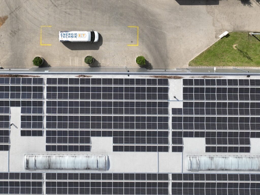 Flachdach mit Solarpaneelen, davor ein Bulli mit Energie Technik Beschriftung