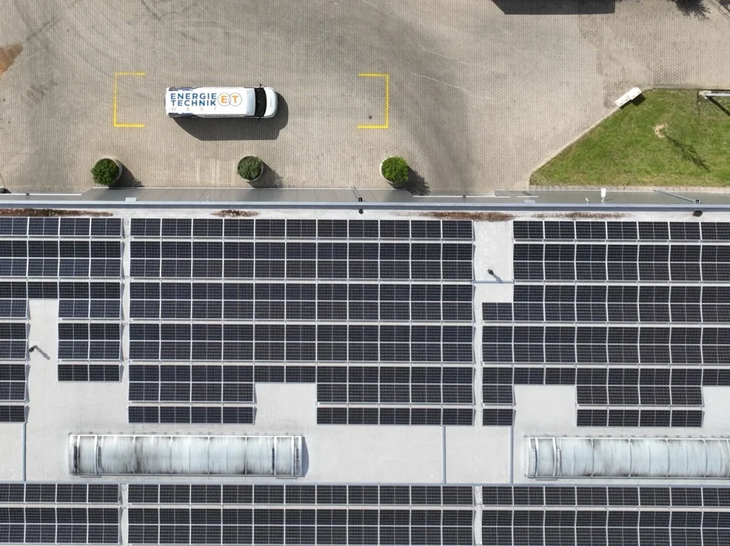 Flachdach mit Solarpaneelen, davor ein Bulli mit Energie Technik Beschriftung