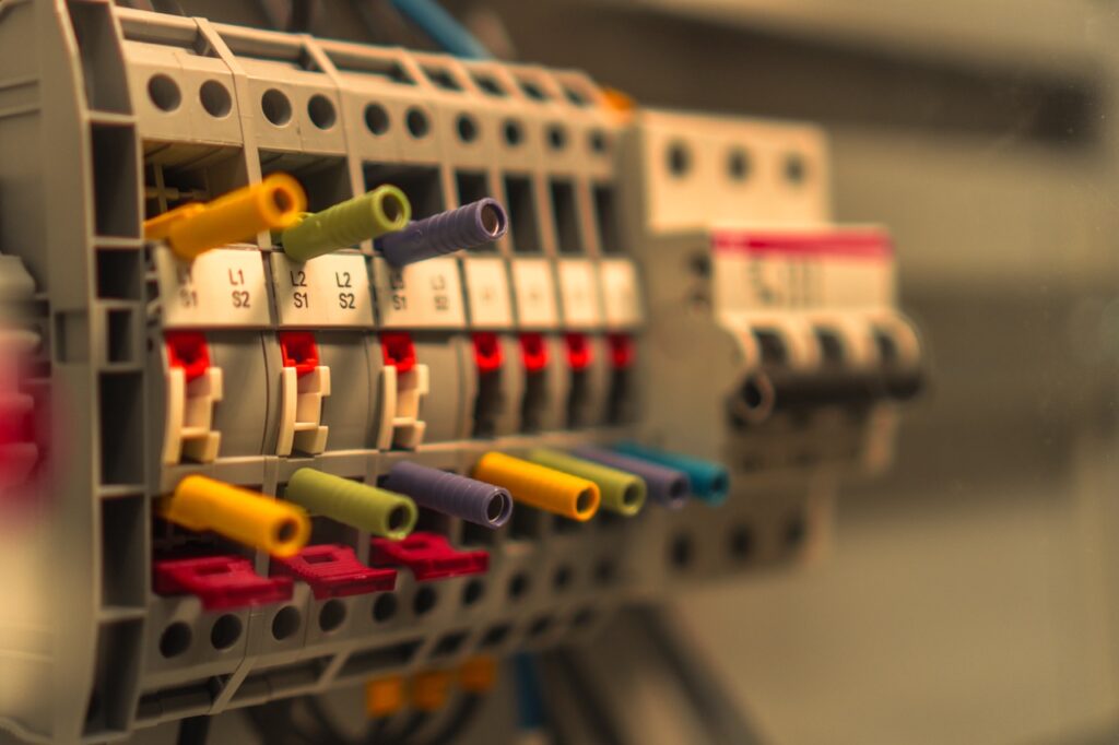 Mehrfarbige Kabel stecken in einer elektrischen Verteilerbox in industrieller Umgebung.