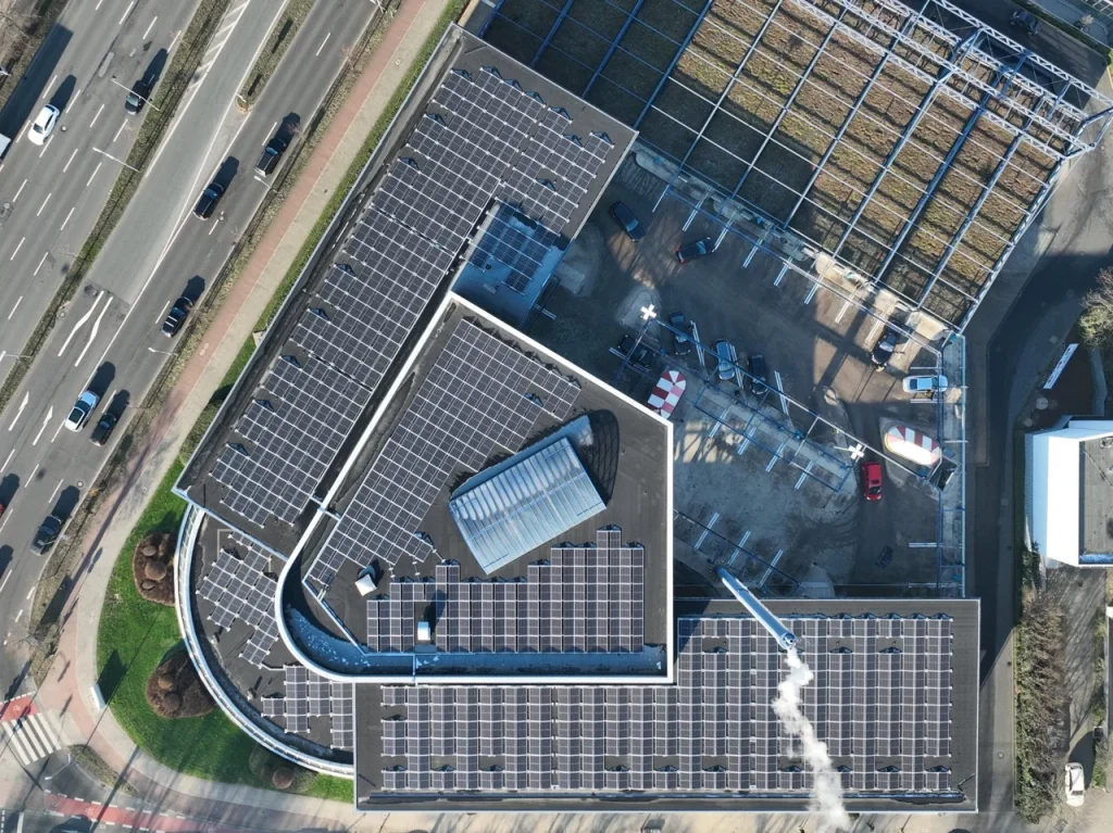 Solarmodule bedecken ein Dach, daneben Baustelle, Autos parken, Straße links, urbanes Gebiet.