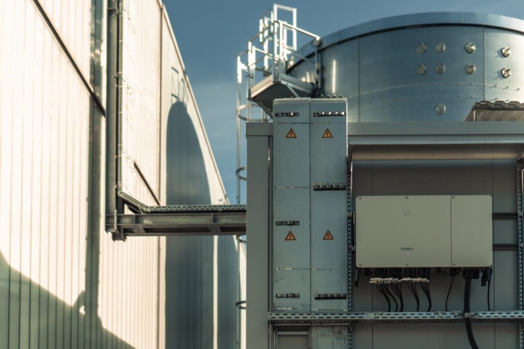 Metallstruktur hängt an der Gebäudewand, zeigt Warnhinweise, im industriellen Bereich.