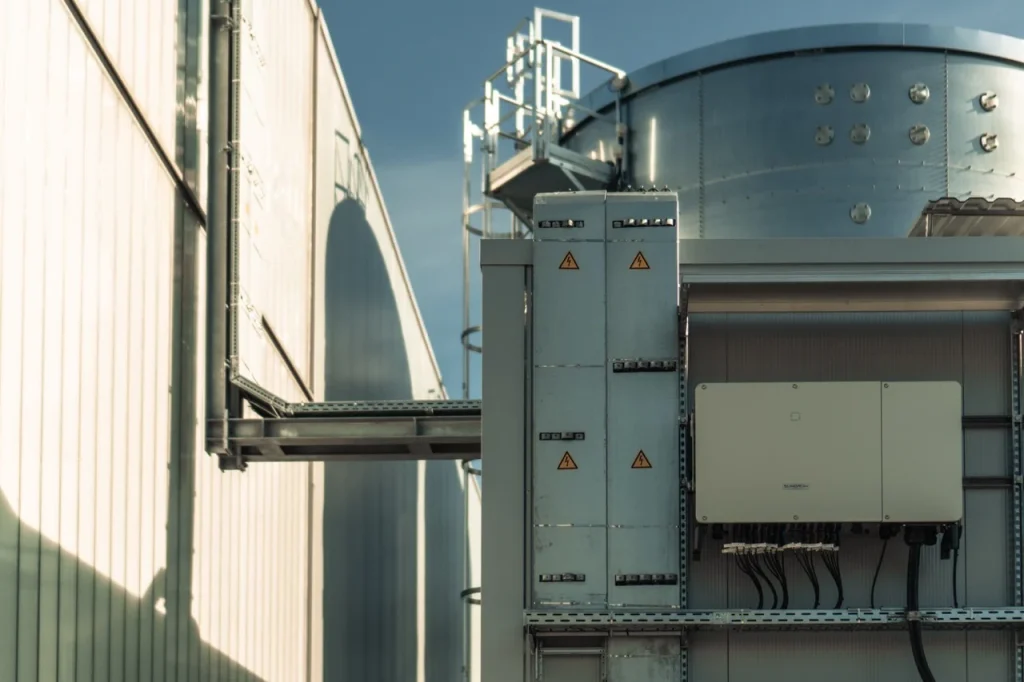Metallstruktur hängt an der Gebäudewand, zeigt Warnhinweise, im industriellen Bereich.