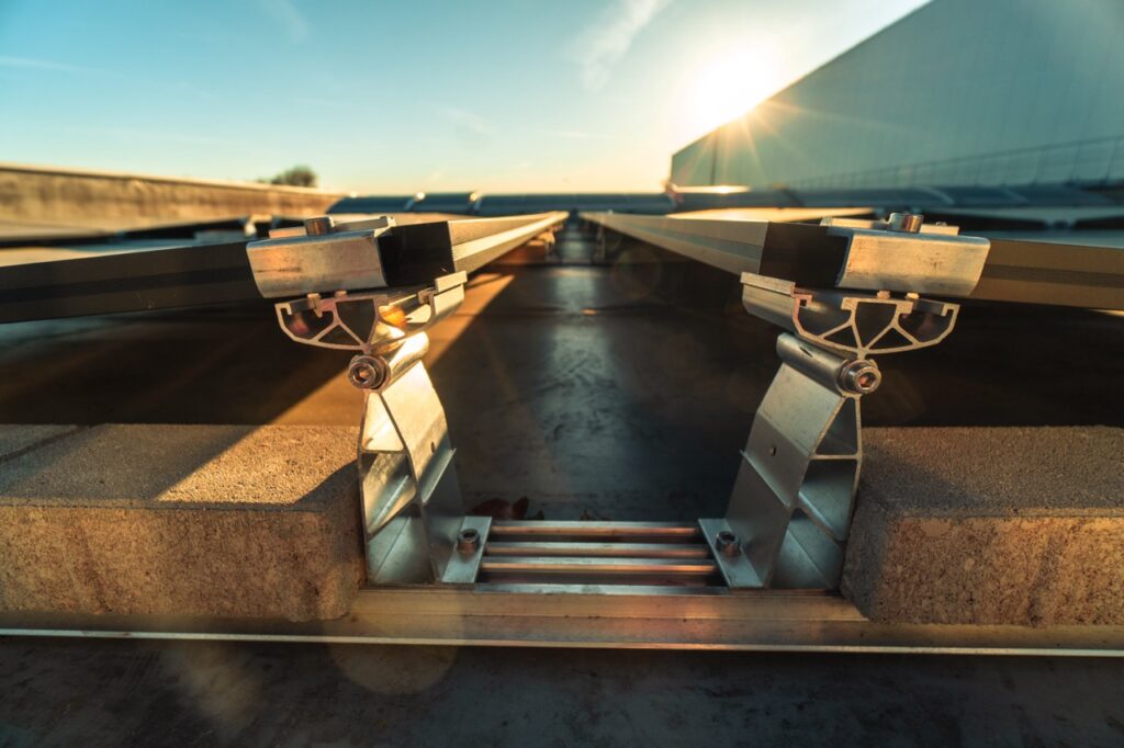 Metallische Halterungen sichern solare Paneele auf einem Dach bei Sonnenuntergang.