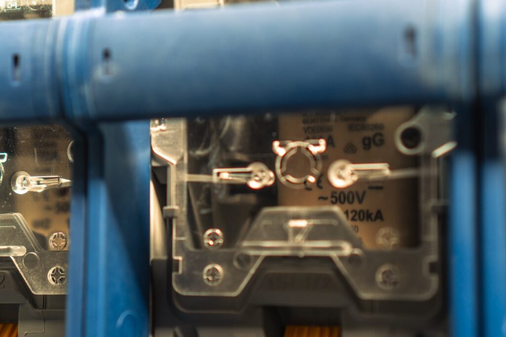 Elektrischer Schaltschrank; Kontaktpunkte sichtbar; Text: „~500V, 120kA“; umgeben von blauem Rahmen.