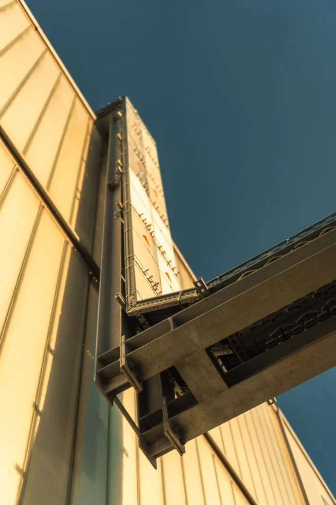 Metallstruktur hält Geräte mit Kabeln, montiert an einer Wand, mit Sonnenlicht im Hintergrund.